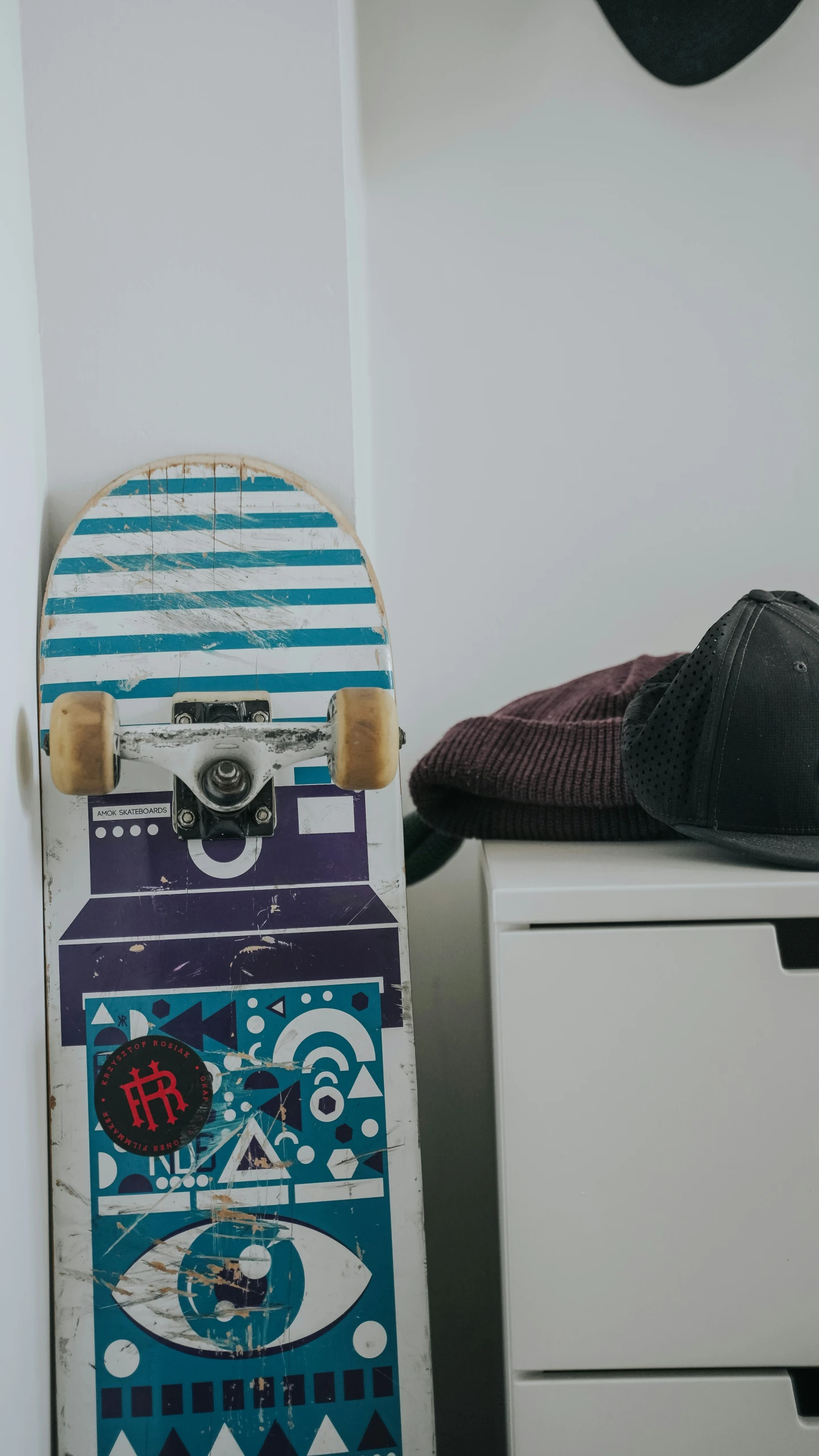 a blue and white skateboard next to a hat