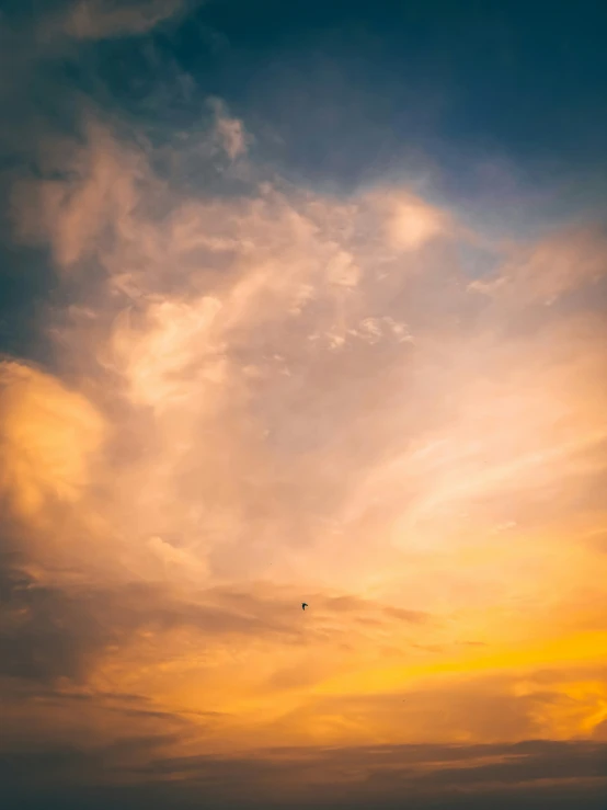 an airplane flying high in the sky as the sun sets