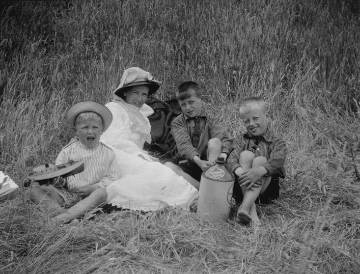 several children and one adult sitting outside in a field