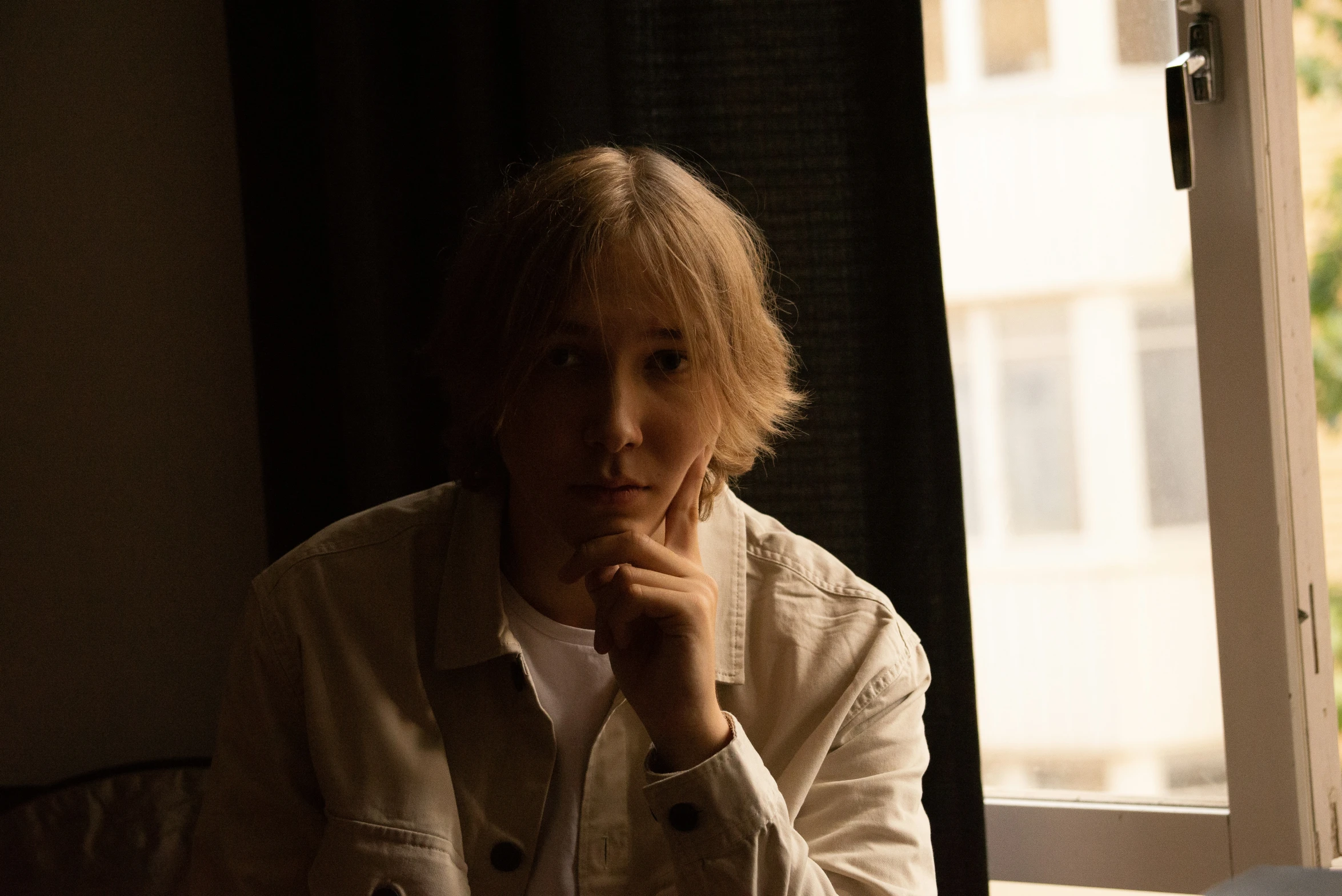 a woman in a jacket sitting at a table in front of a window