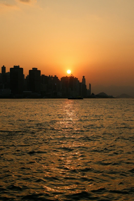 the sun is setting over a city, a bay and water