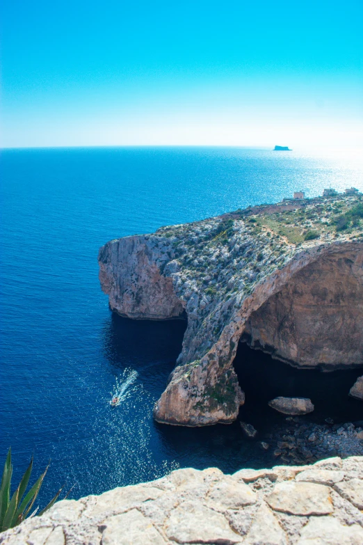 an area with rocks and blue water near a large cliff