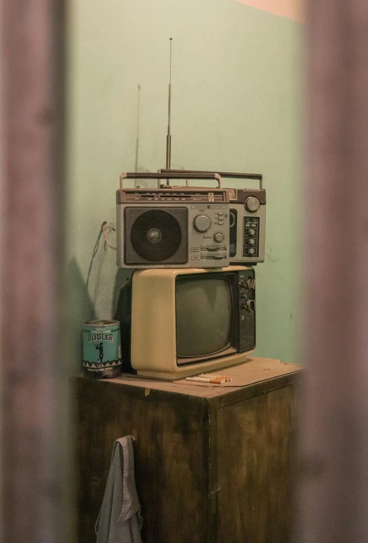 three old and rusty televisions sitting on a wooden table