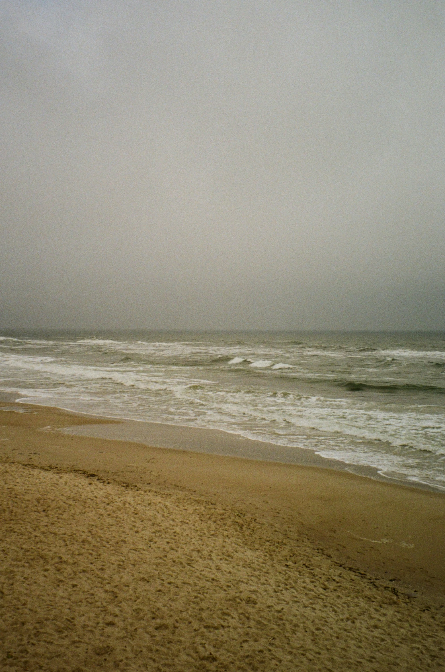 the person is walking toward the water on the beach