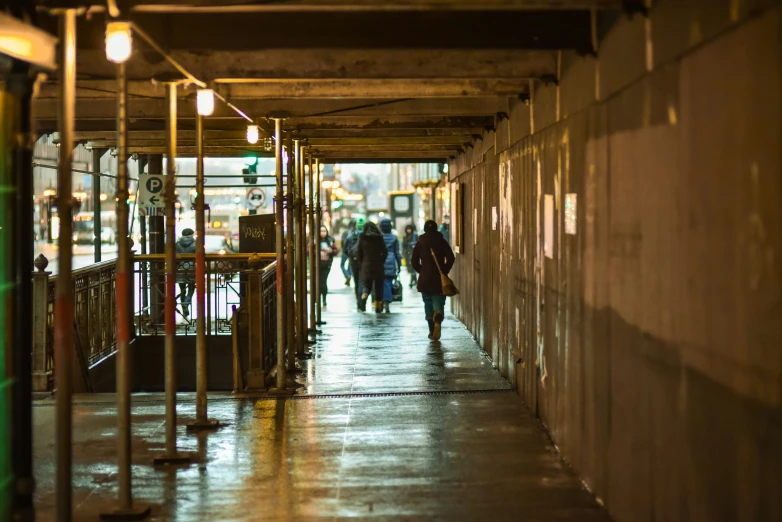 people are walking down a rain covered walkway