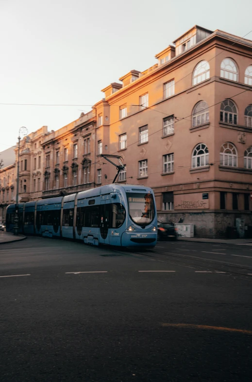 a blue bus on street next to a tall building