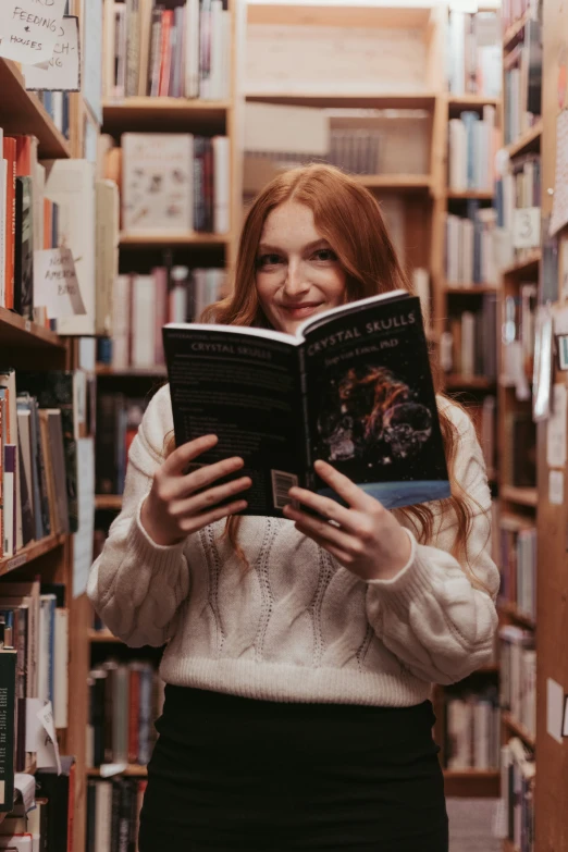 the smiling woman is reading a book in a liry