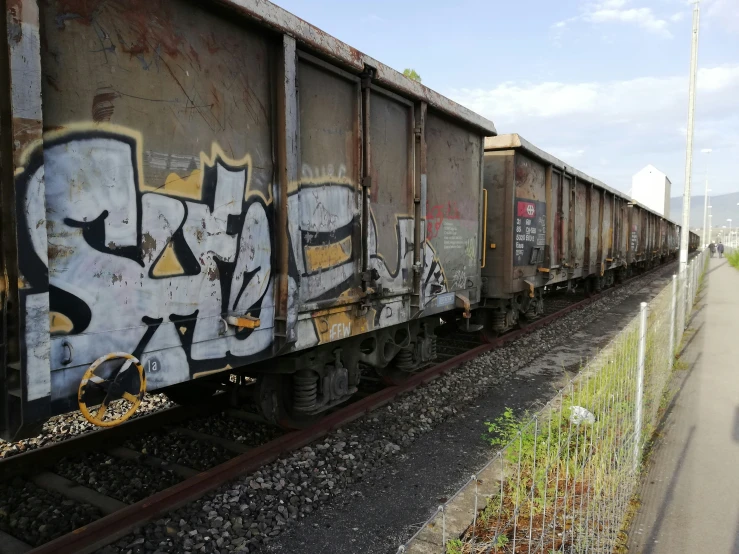graffiti art on side of train car with railroad tracks