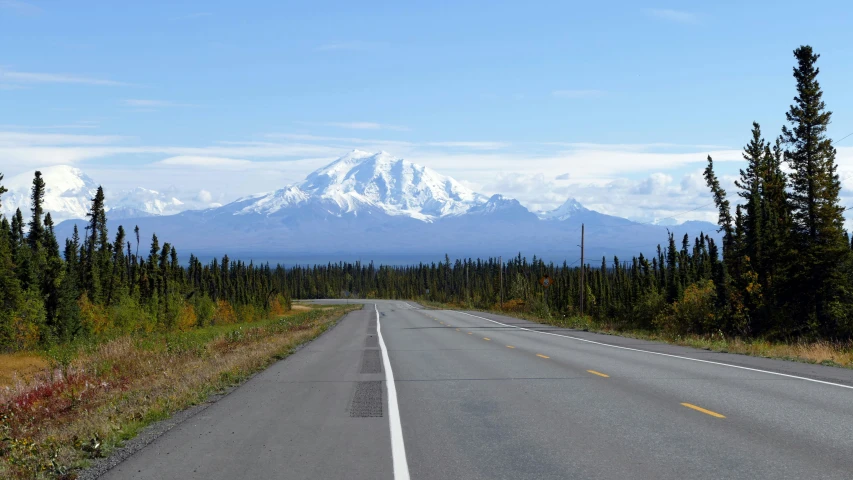 the mountain range and the road are lined with trees