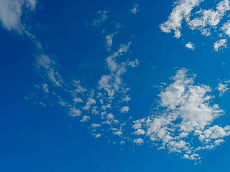 a plane flying through the blue sky with white clouds