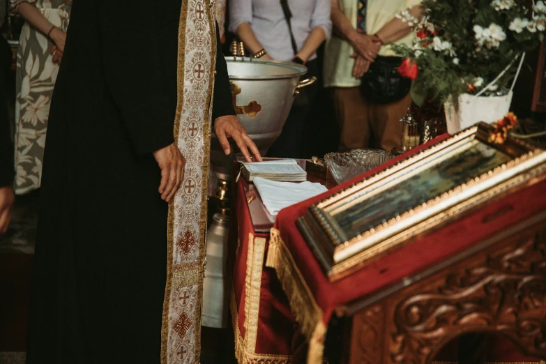 a priest looking at the altar as others stand in the background