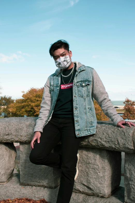 a man with a face mask sitting on a cement wall