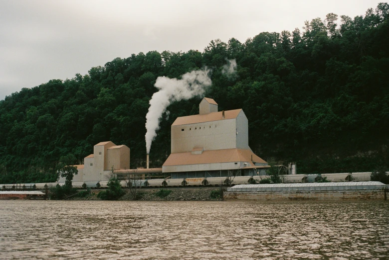 two smoke stacks are billowing smoke while another steams out