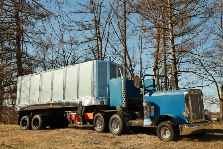 a large semi truck with trailer on a dirt lot