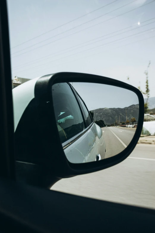 a car is seen in the rearview mirror of it's side view mirror