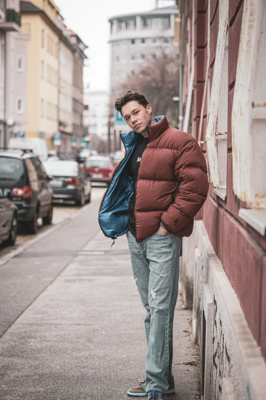 a man standing against a building while wearing a red jacket