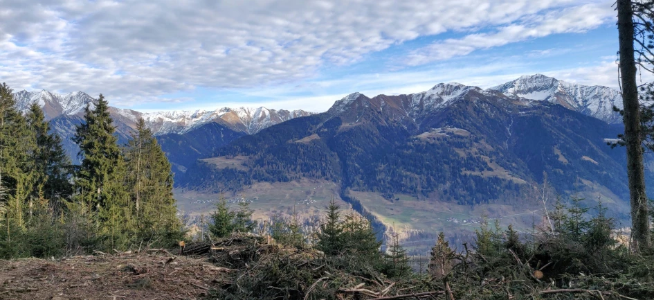 some very tall mountains with a bunch of trees in the foreground