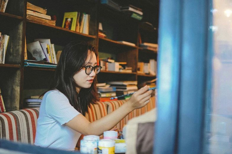 woman in glasses sitting at desk with books