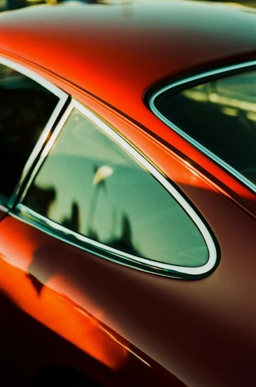 the reflection of someone in the rear view mirror of a red car