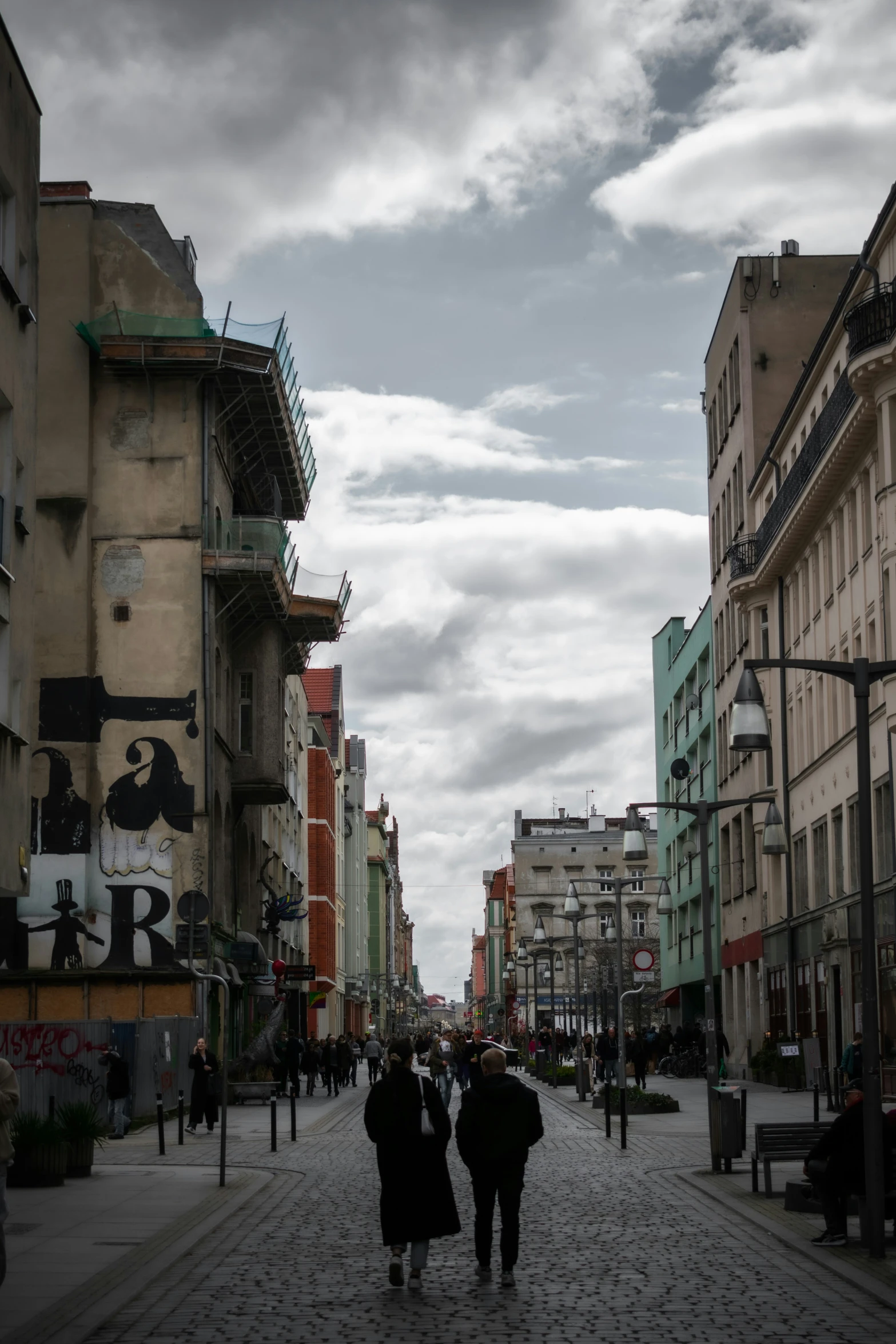 a group of people walking down a city street in front of a traffic light