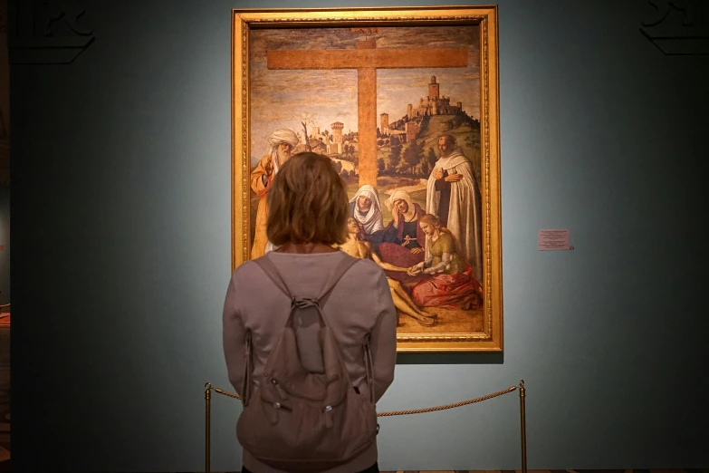 a woman looks at a painting that is hanging on a wall