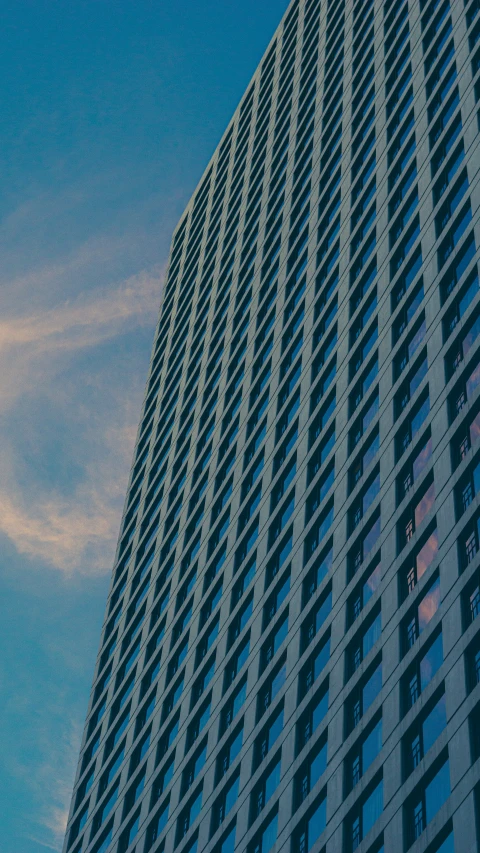 a plane flying by a tall building in the evening