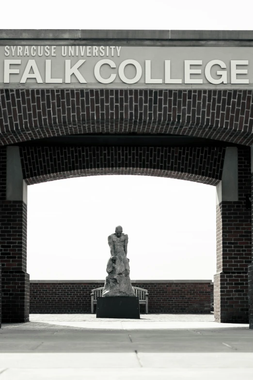 a stone statue is under an archway that says a college