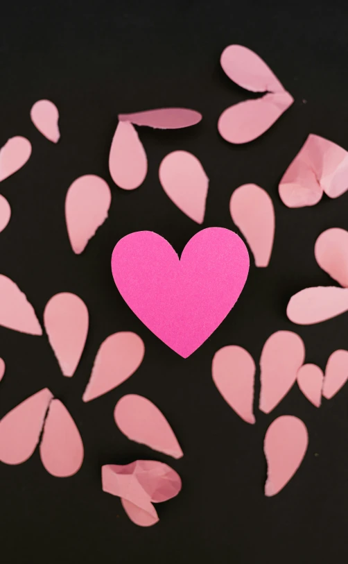 a pink heart surrounded by petals of pink paper