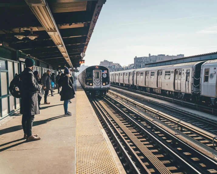 people stand on the platform and wait for the train