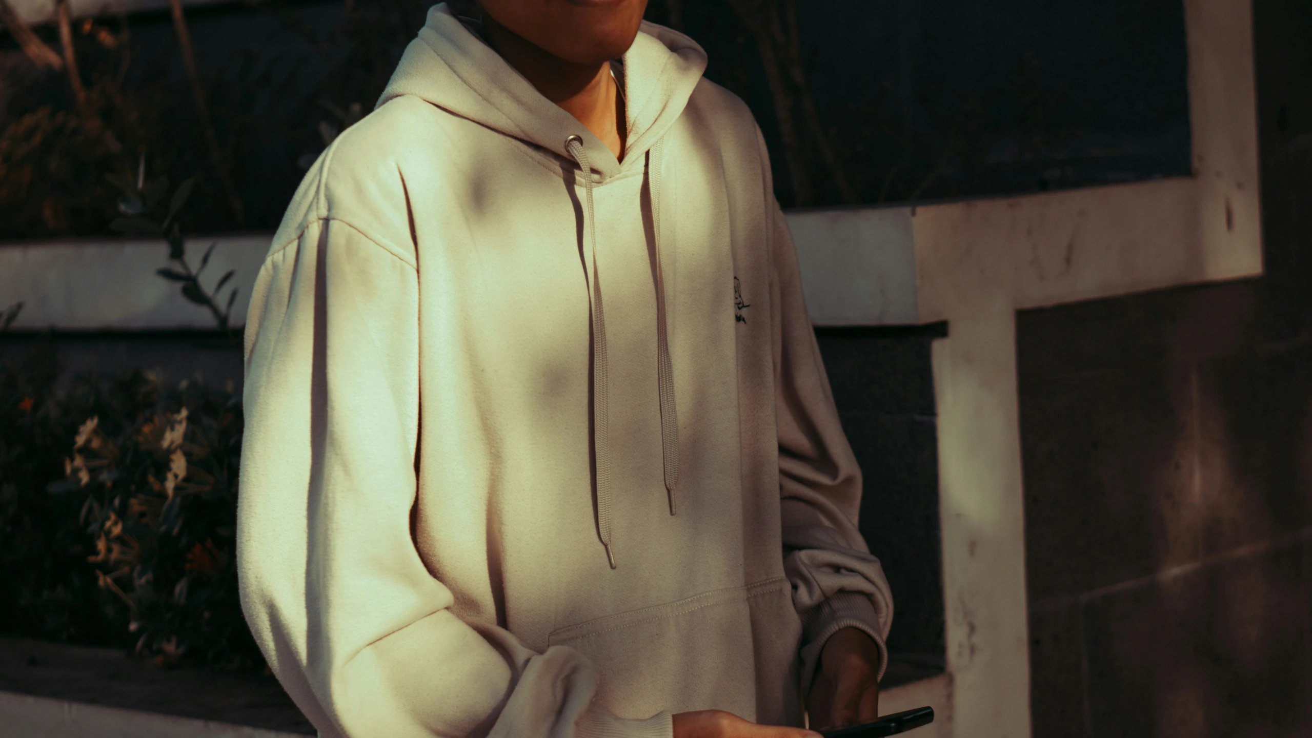 man wearing a white shirt standing in front of a building with his eyes closed