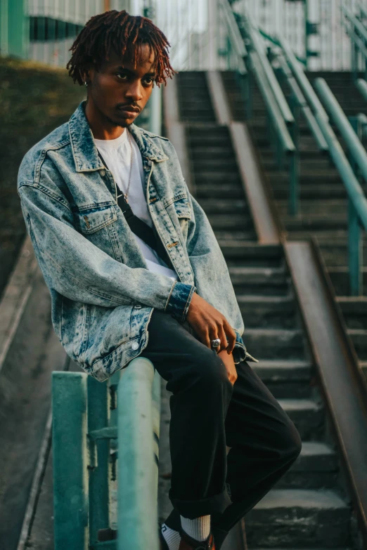 man with dreadlocks sits on the steps at the foot stairs