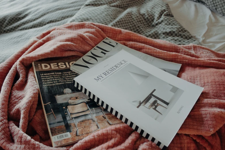 an open book and magazine lying on top of a bed