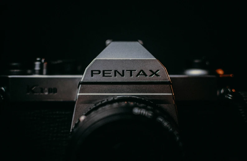 a pentax po camera in black with an lens attached