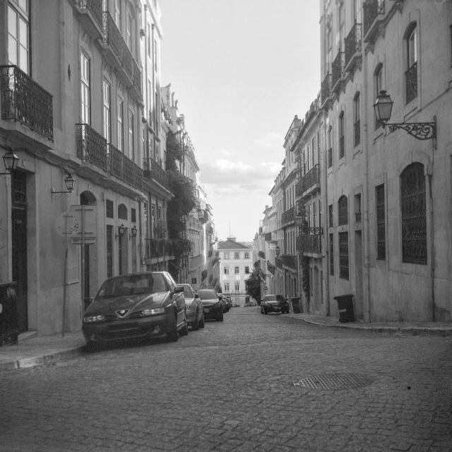 cars on the street in an alley between two buildings