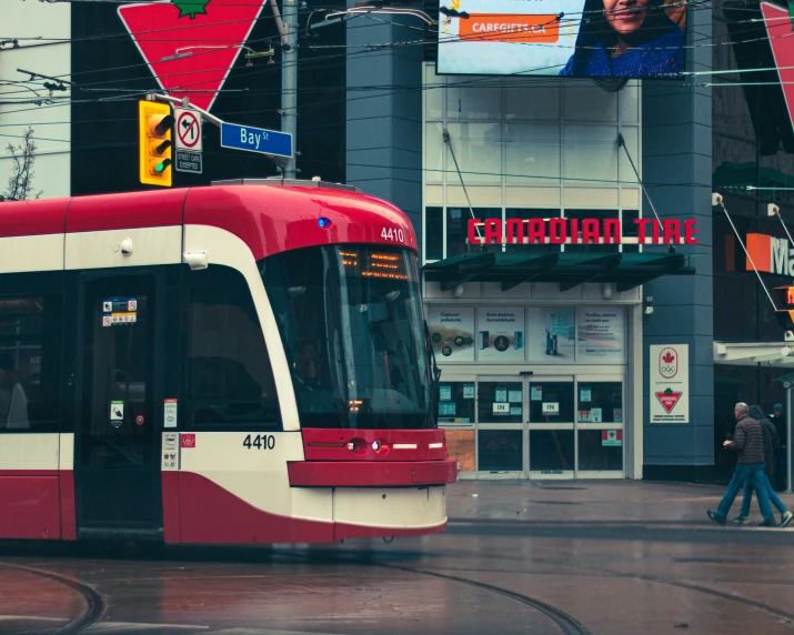 a red and white train traveling past tall buildings