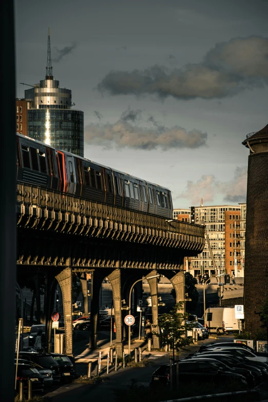 a train going across a bridge by some tall buildings