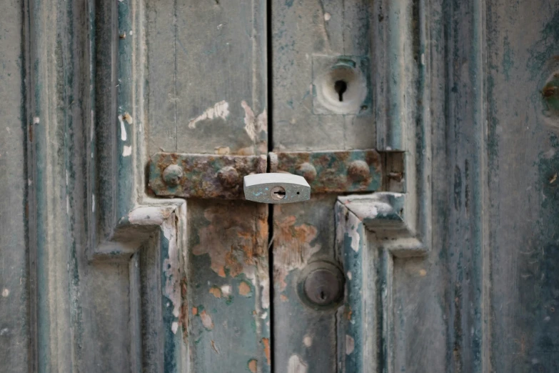 a worn and dirty wooden door with a lock on it