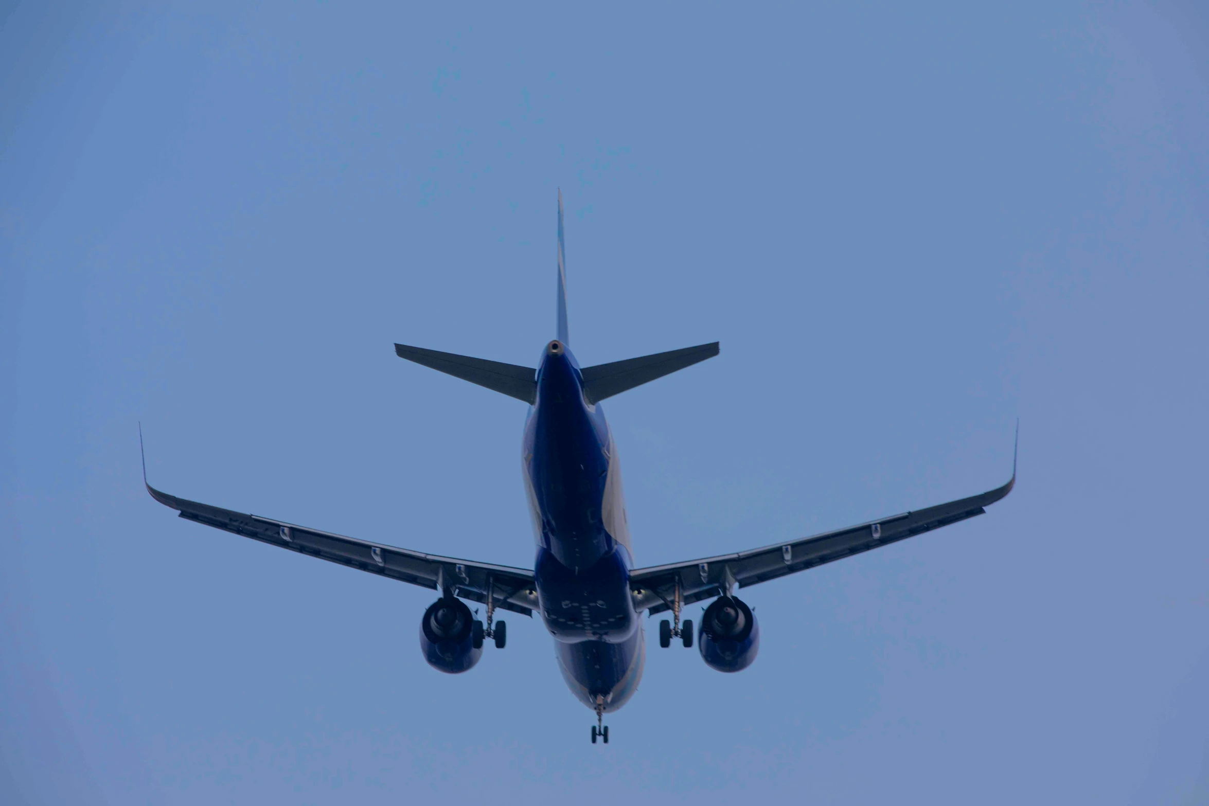 an airplane with it's landing gear down, flying over head