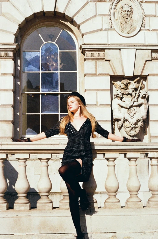 the girl in black dress is leaning on a stone wall