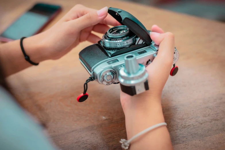 the girl is playing with her small, old - fashioned camera