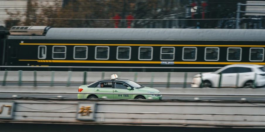 the car is driving in traffic as a train passes by