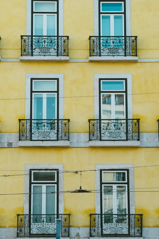 three balcony windows of a yellow building