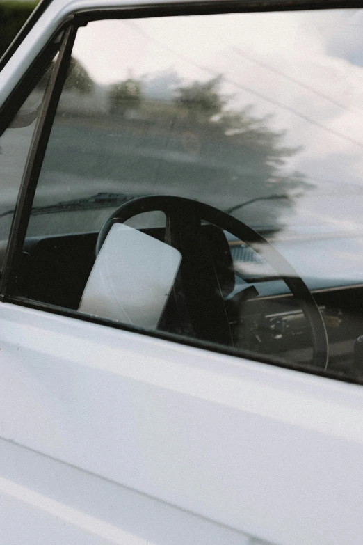 an open car window reflecting a white van's interior