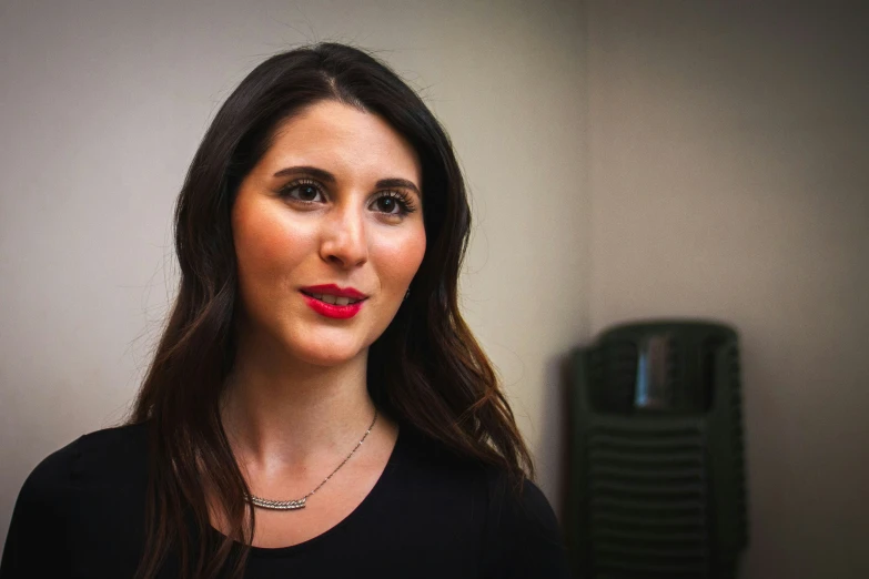 a woman wearing red lipstick standing in front of a wall