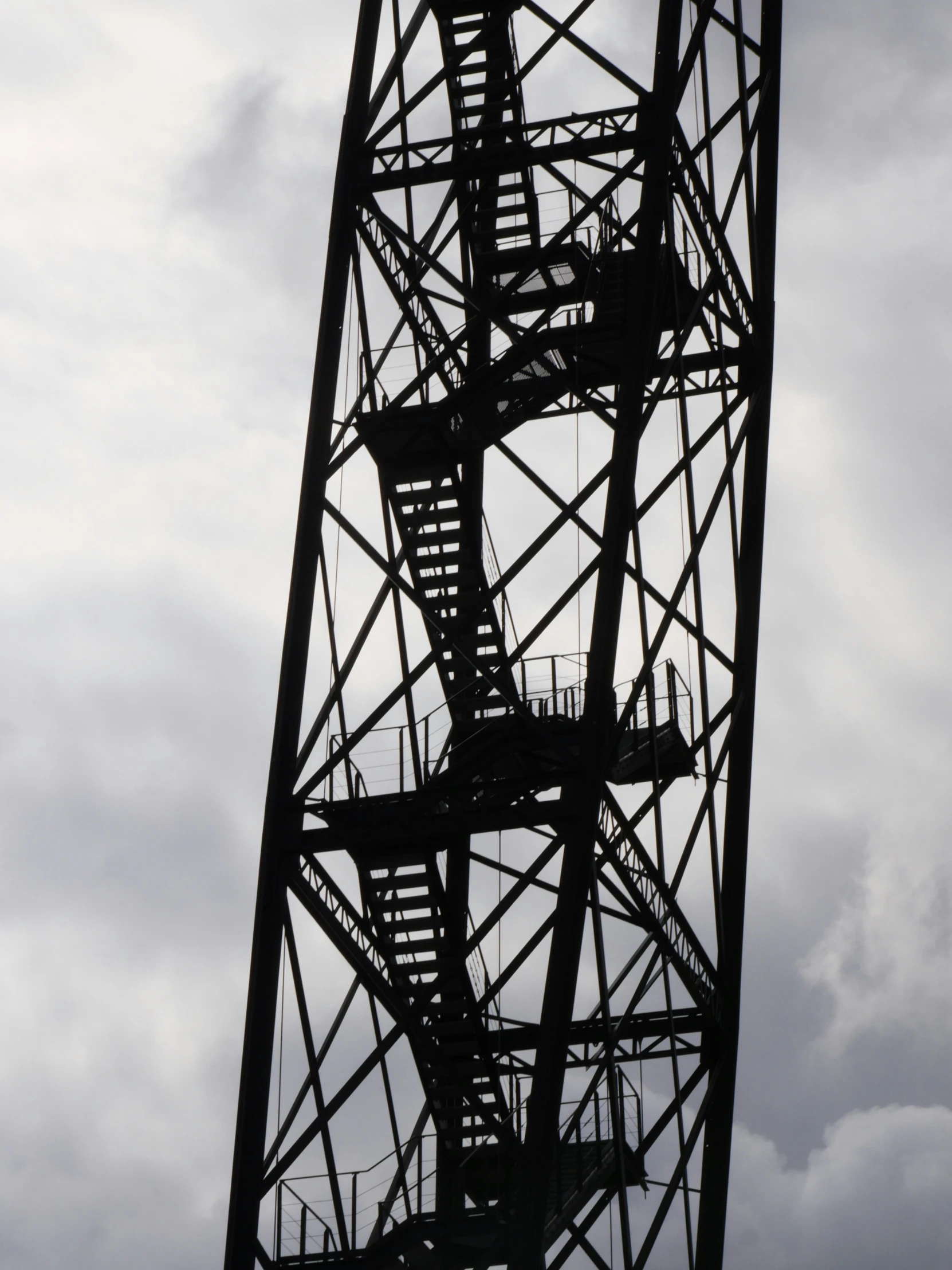 a tall metal tower structure on top of a cloudy sky