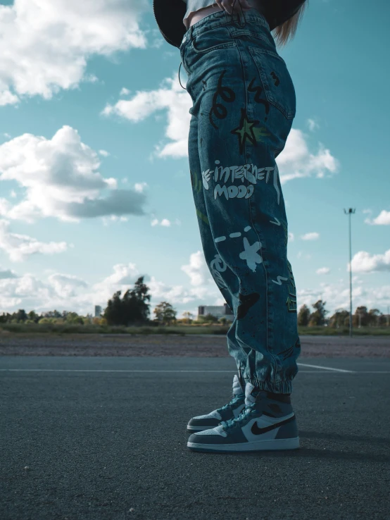 a person standing on the sidewalk in their jean pants