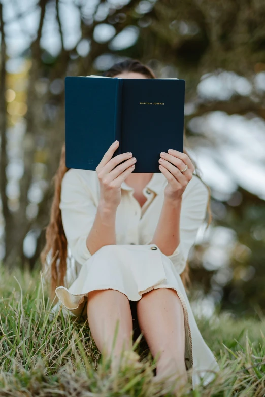 a woman reads a book outdoors in the grass