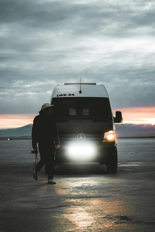a man walking next to his van at dusk