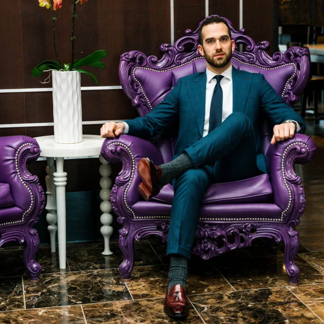 the man is sitting in a fancy chair and posing for a po