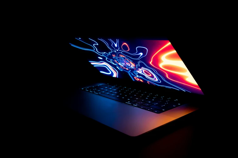 an apple laptop on a black table in the dark